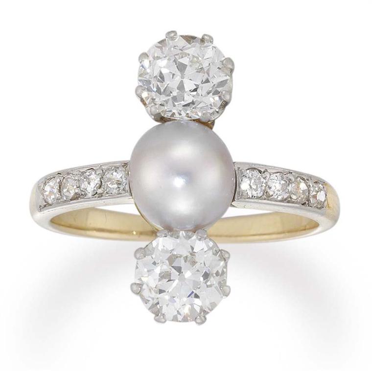 This beautiful Edwardian diamond and cultured pearl three-stone ring circa 1910, available at Bentley & Skinner, has a central cultured pearl set between two old brilliant-cut diamonds, all vertically set, to a gold open-backed mount with diamond-set shou